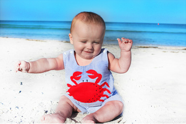 Baby wearing a crab shirt at the beach